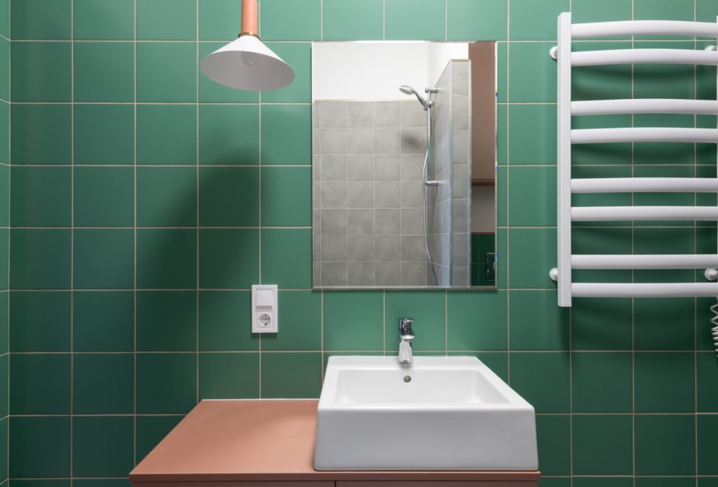 Elektriciteit in de badkamer - wastafel met groene tegels